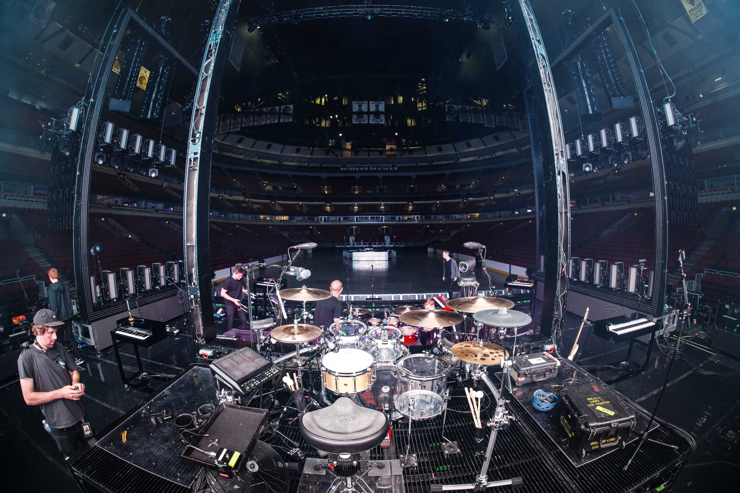 Drum tech Tom 'Woody' Wood behind drum kit of The 1975 drummer George Daniel